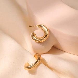 Dettaglio degli orecchini a cerchio a C placcati oro 18K su elegante pietra materica