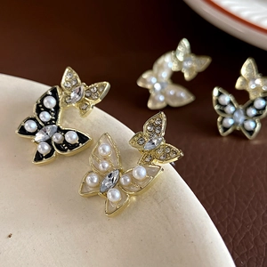 Detail view of butterfly earrings with pearls and rhinestones on a ceramic dish