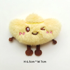 Detail of yellow plush doll with cartoon embroidery and soft texture in 6.5x7cm size