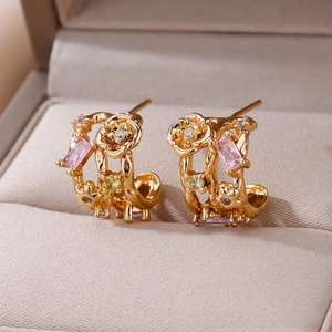 Detailed close-up of C-shaped floral earrings with pink and yellow crystals in a beige box