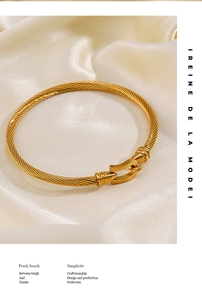 Macro detail of golden twisted cable bracelet with horseshoe buckle on silk background