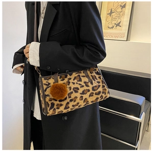 Close-up of leopard print plush shoulder bag with brown pompom and leather strap