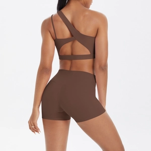 Detail of cross open back design on deep brown one shoulder sports bra and shorts