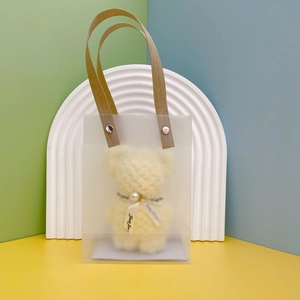 Frosted gift bag with teddy bear towel, brown handles, and metal rivet details