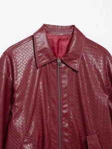 Close-up of dark red woven faux leather bomber jacket with collar and metal zipper