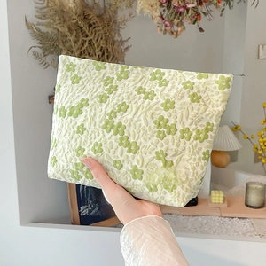 Close-up of light green floral jacquard makeup bag with May Rabbit label and zipper