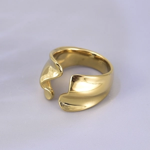 Macro shot of gold wide band irregular wavy ring with smooth metallic luster