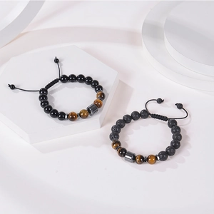 Detailed close-up of 10mm lava stone and tiger eye beaded bracelets on a white stone base