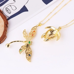 Gold dragonfly and turtle necklaces with colorful zircons on an artistic background