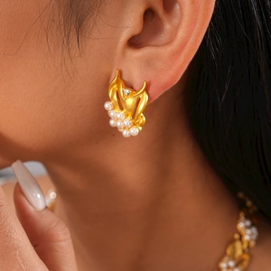 Elegant gold flower earrings with white pearls and sparkling zircons on female model