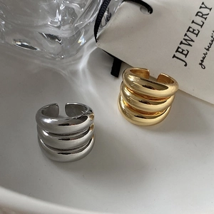 Three-layer geometric open rings in gold and silver finish on elegant display