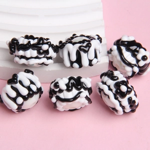Macro view of handmade black and white glass beads for DIY jewelry on pink background