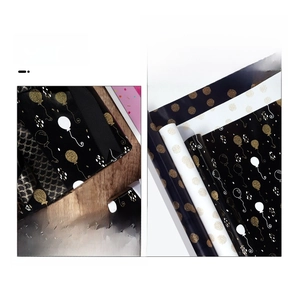 Detail of black and white birthday wrapping paper with gold foil balloons and patterns