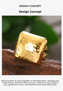 Macro shot of gold square ring with vintage hammered texture on dark wood surface