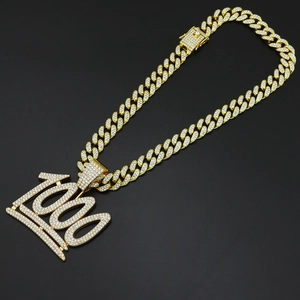 Gros plan du pendentif 100 doré serti de cristaux sur une chaîne maille cubaine