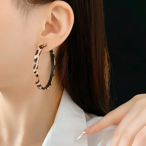 Gros plan de boucles d'oreilles créoles en cuir léopard portées par un mannequin chic
