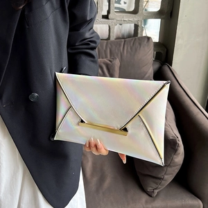 Detail of holographic white envelope clutch with gold metal bar and trim shown by model