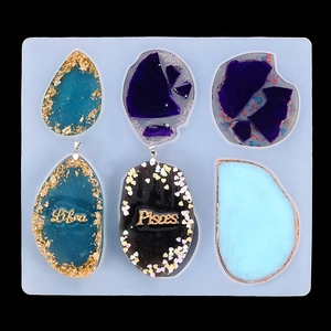 Detail of 6-cavity blue silicone mold with resin pendants featuring gold foil and glitters