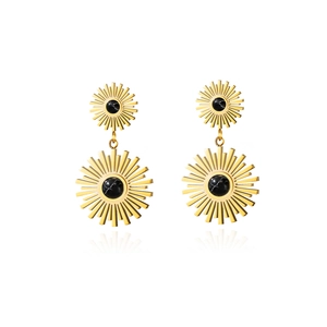 Detail view of golden starburst earrings with natural black stone inlays on white background