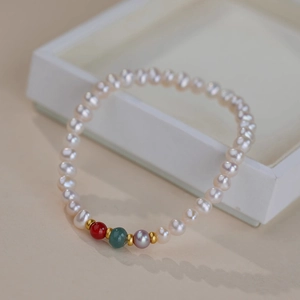 Detail of freshwater pearl bracelet with agate beads and gold spacers on white background