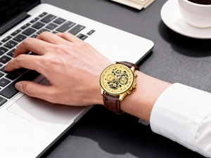 Men's quartz watch with gold case and brown leather strap on wrist in business office