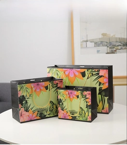 Three tropical floral paper gift bags with hibiscus prints and gold rope handles