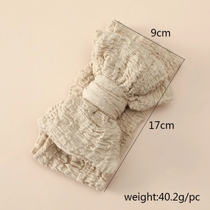 Close-up of beige oversized bow headband showing textured fabric and 9x17cm dimensions