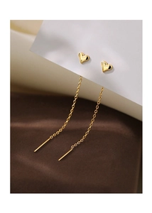 Macro detail of gold heart-shaped stud earrings with delicate long tassel chains