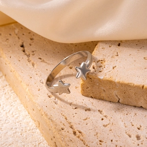 Detail shot of a silver star open ring made of stainless steel on beige stone