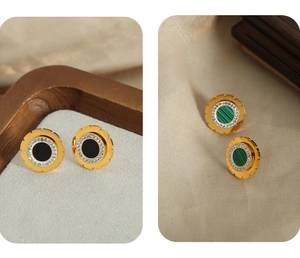 Detailed close-up of gold-plated gear earrings with black acrylic and green malachite inlay