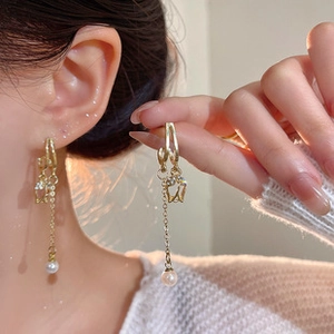 Close-up of golden tassel earrings with elegant tulip design and pearl drop on model