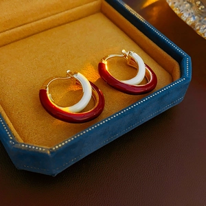 Gros plan sur les boucles d'oreilles C en émail rouge et blanc dans un coffret en velours