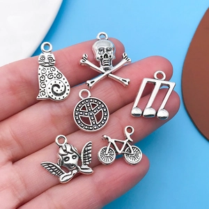 Macro shot of silver Tibetan alloy charms including cat and musical note on a hand palm