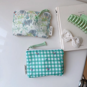 Mini pochettes en coton à fleurs et carreaux verts avec fermeture sur table blanche