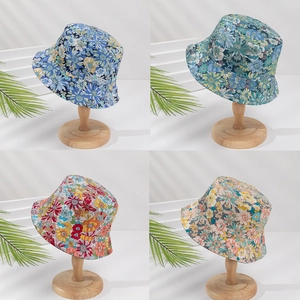Floral bucket hats in blue green red and pink colors shown on wooden stands