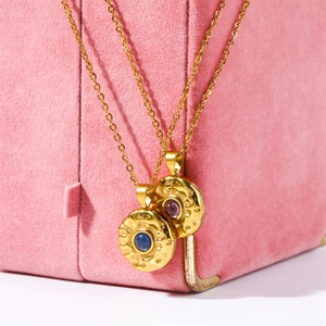 Detailed view of hammered gold birthstone pendants with blue and purple gemstones