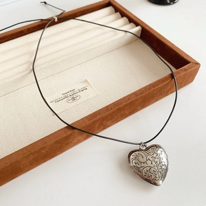 Detail shot of vintage carved heart pendant on adjustable black rope in jewelry tray