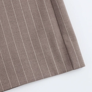 Detailed close-up of brown pinstripe fabric texture on professional suit trousers