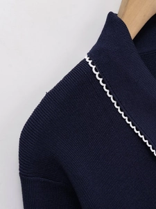 Detail of dark blue knit top featuring contrast white scallop edge on the collar