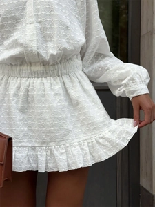 Détail de la robe blanche avec broderie en cœur et finitions à volants doux
