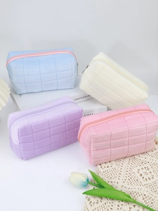 Detailed stack of four pastel quilted velvet makeup bags in a clean lifestyle setting
