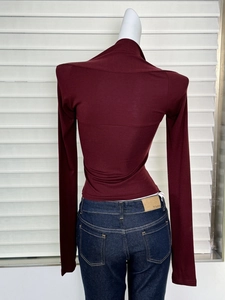 Détail d'un haut ajusté bordeaux à manches longues avec un jean en denim bleu foncé