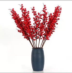 Vibrant red berry branches in a matte dark blue ceramic vase for home decoration