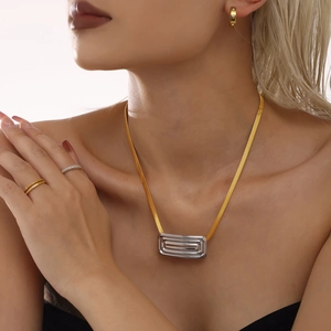 Flat gold snake chain necklace with silver layered rectangular pendant worn by a model