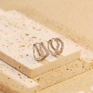 Detail of silver double-layer crystal earrings on textured beige stone plates