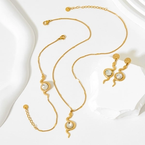 Macro shot of gold snake jewelry set with sparkling crystal pendants and scale texture