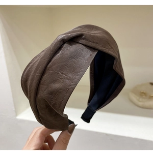 Detail shot of brown faux leather headband showing soft pleated texture and wide cross design