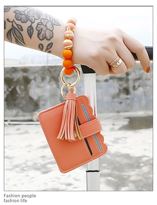 Coral pink leather card holder with beads wristlet hanging on luggage handle