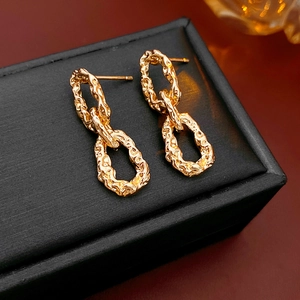 Vue détaillée des boucles d'oreilles dorées à maillons avec texture martelée sur boîte