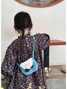 Rear view of a child wearing a handmade crochet flower crossbody bag in blue and white